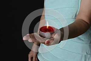 Woman holding burning candle in darkness