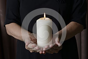 Woman holding a burning candle in the darkness