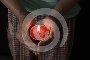 Woman holding a burning candle in the darkness