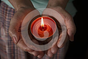 Woman holding a burning candle in the darkness