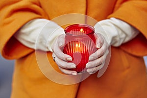 Woman holding burning candle in her hands