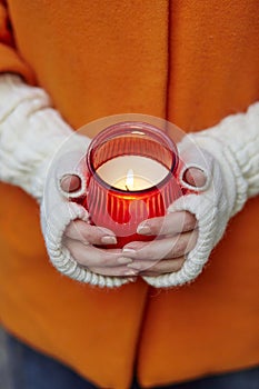 Woman holding burning candle in her hands