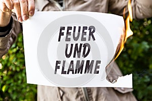 Woman is holding a burning paper with german text