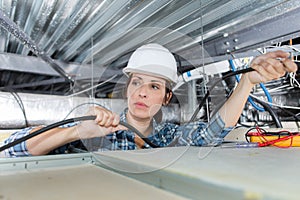 woman holding cables overhead in roofspace