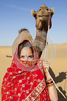 Woman holding a camel in the desert.