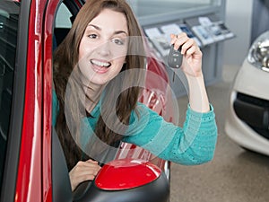 Woman holding car key inside car dealership