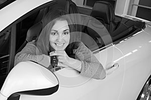 Woman holding car key inside car dealership