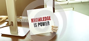 Woman holding card with Knowledge is power text on grey background. Mock up for design