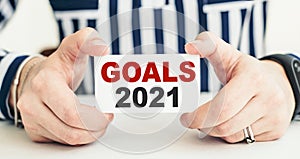 Woman holding a card with a message text written on it GOALS 2021