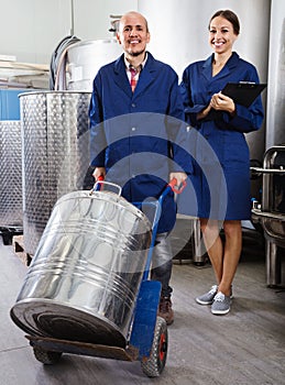 Woman holding cardboard and standing with man working