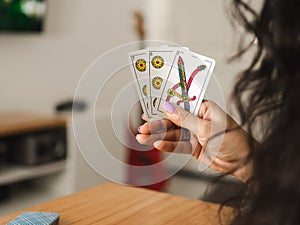 Woman holding cards while playing Truco, an Argentinian card game. Close up photo