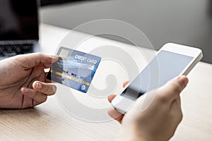 A woman holding a cell phone and credit card, she fills in her credit card information in a mobile shopping app to pay.