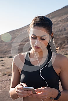 Woman holding a cell phone and has ear phones on