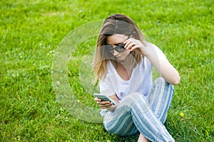 Woman holding cell phone in her hand. Grass background, spring park