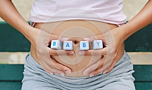 Woman holding character cubic `BABY` at her belly