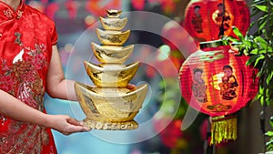 Woman holding Chinese new year gold ingots Qian in Chinatown