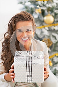 Woman holding christmas present box in front of christmas tree