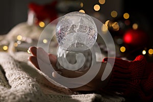 Woman holding Christmas snow globe on blurred background