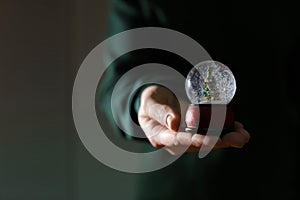 Woman holding Christmas snow globe on blurred background, closeup.