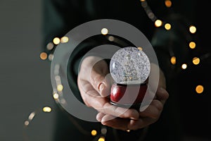 Woman holding Christmas snow globe on blurred background. Space for text