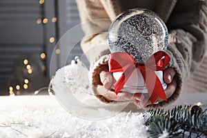 Woman holding Christmas snow globe with red bow