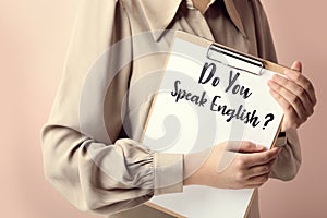 Woman holding clipboard with question Do You Speak English on pink background, closeup