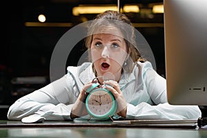 Woman holding a clock. Woman holds an alarm clock in her hand in the workplace