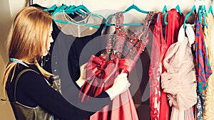 Woman holding a clothes hanger with a evening dress. Women fashion. Fashionable dress. Red Party Dress. Girl in dressing room