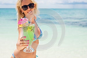 Woman holding cocktail on the beach