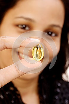 Woman holding cod liver oil capsule