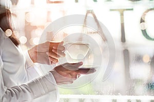 Woman holding coffee cup in a cafe on raindrop background