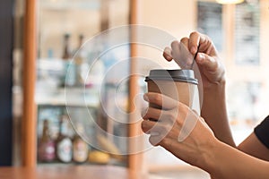 A woman is holding a  coffee cup in coffee`s shop at noon