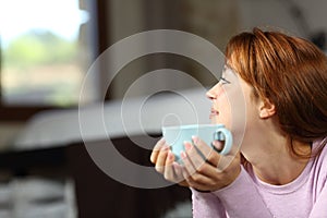 Woman holding coffee cup contemplating in the bedroom