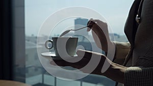 Woman holding coffee cup and spoon and stirring fresh hot coffee