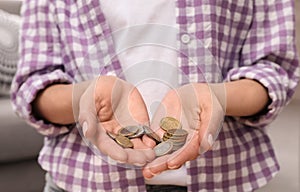 Woman holding coins at home, focus on hands