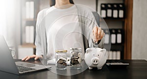 Woman holding coins putting in glass with using smartphone and calculator to calculate concept saving money for finance accounting