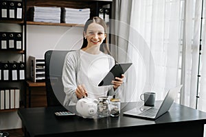 Woman holding coins putting in glass with using smartphone and calculator to calculate concept saving money for finance accounting