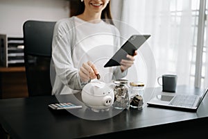 Woman holding coins putting in glass with using smartphone and calculator to calculate concept saving money for finance accounting