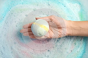 Woman holding color bath bomb over foam
