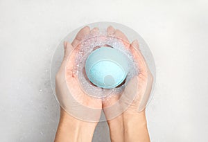 Woman holding color bath bomb over foam