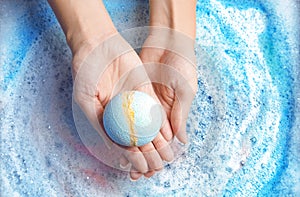 Woman holding color bath bomb over foam