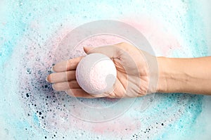 Woman holding color bath bomb over foam