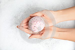 Woman holding color bath bomb over foam