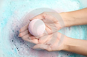 Woman holding color bath bomb over foam