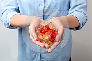 Woman holding colorful jelly bears on light background