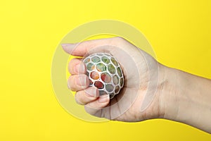 Woman holding colorful slime on yellow background, closeup. Antistress toy