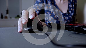 Woman holding a computer mouse, clicking and scrolling, close up. Lady working on computer at home in the dark at night