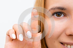 Woman holding of contact lens on the tip of the finger close to the face