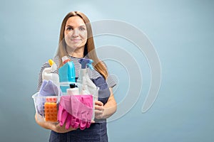 Woman holding a container with a set of cleaning products on blue background