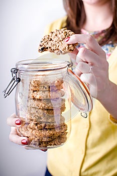 Woman holding cookie jar with cookies in one hand